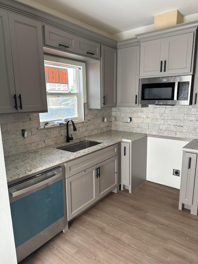 218 Michael Ave, Dumas, TX 79029 - kitchen with dishwasher, stainless steel microwave, a sink, gray cabinetry, and backsplash