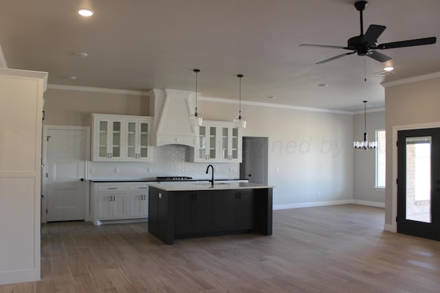 8104 Miami Ave, Amarillo, TX 79118 - kitchen with custom exhaust hood, wood finished floors, white cabinets, an island with sink, and a sink