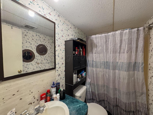 bathroom featuring toilet, wallpapered walls, a shower with curtain, and a sink