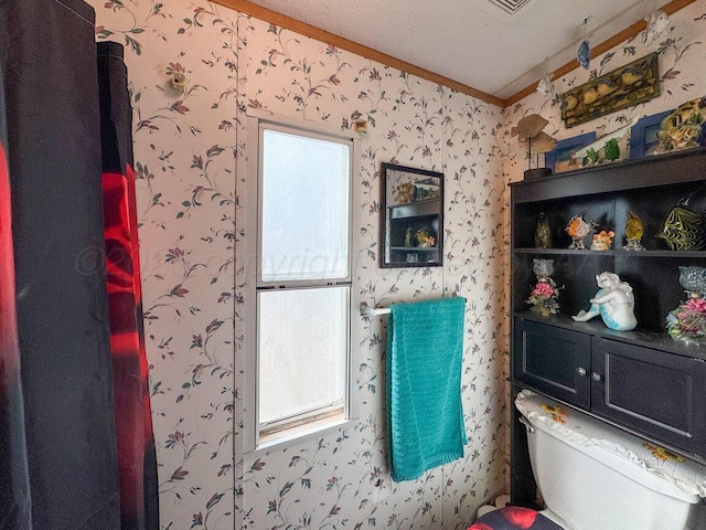 bathroom with ornamental molding, toilet, and wallpapered walls