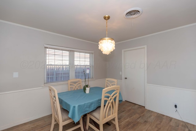 dining area with wood finished floors, crown molding, and a chandelier