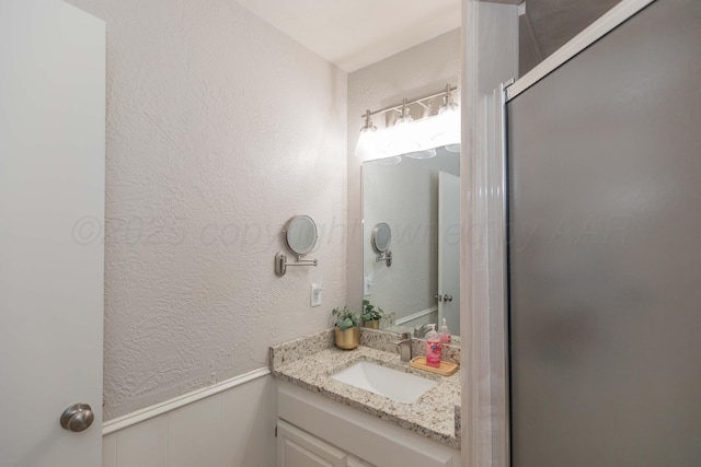 bathroom with a wainscoted wall, vanity, and a textured wall