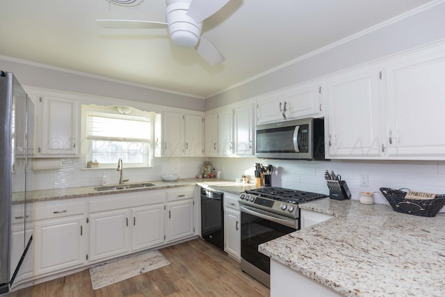 kitchen featuring appliances with stainless steel finishes, a sink, a ceiling fan, white cabinets, and light wood finished floors