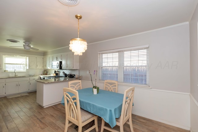 dining room with light wood-style floors, ornamental molding, baseboards, and a chandelier