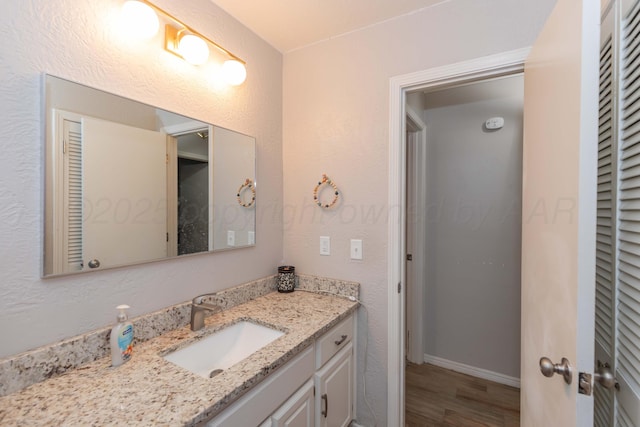 bathroom featuring wood finished floors, vanity, and baseboards