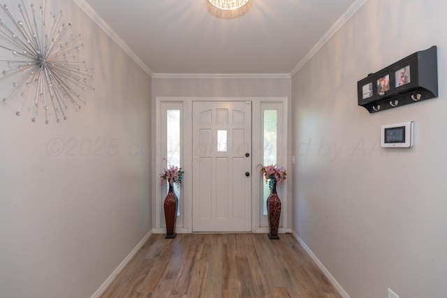 foyer entrance with wood finished floors, baseboards, ornamental molding, and a chandelier