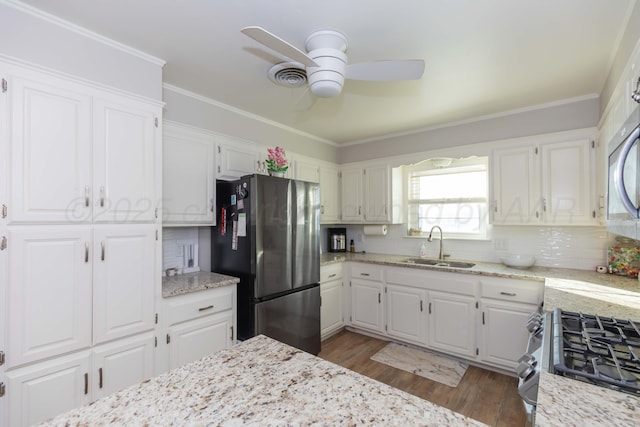 kitchen with stainless steel appliances, ceiling fan, tasteful backsplash, a sink, and white cabinets