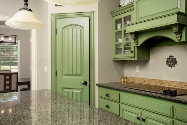 kitchen with green cabinetry, black electric stovetop, glass insert cabinets, custom range hood, and dark stone counters