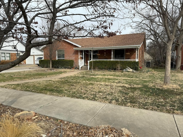 view of front of home with brick siding, roof with shingles, covered porch, a garage, and a front lawn