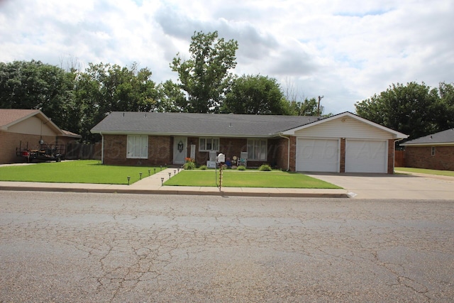 single story home featuring driveway, brick siding, a garage, and a front yard