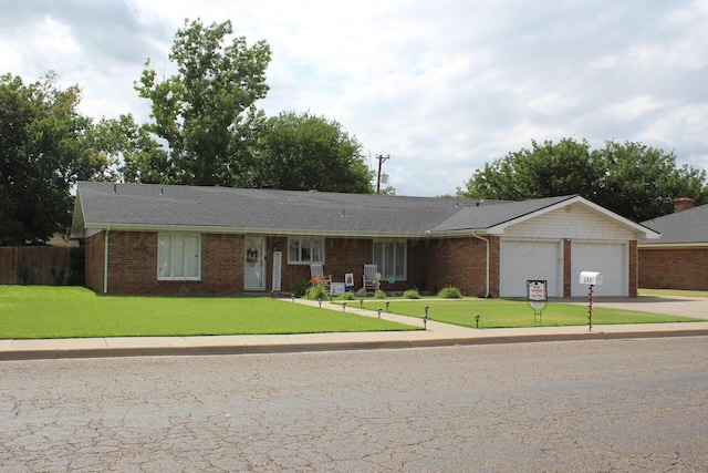 single story home featuring a garage, a front lawn, concrete driveway, and brick siding