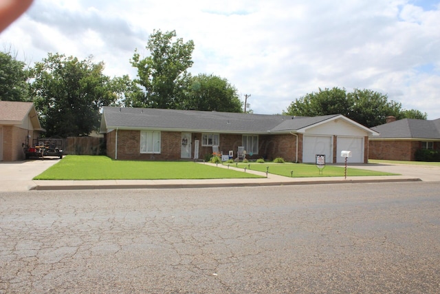 single story home with a garage, a front yard, brick siding, and fence