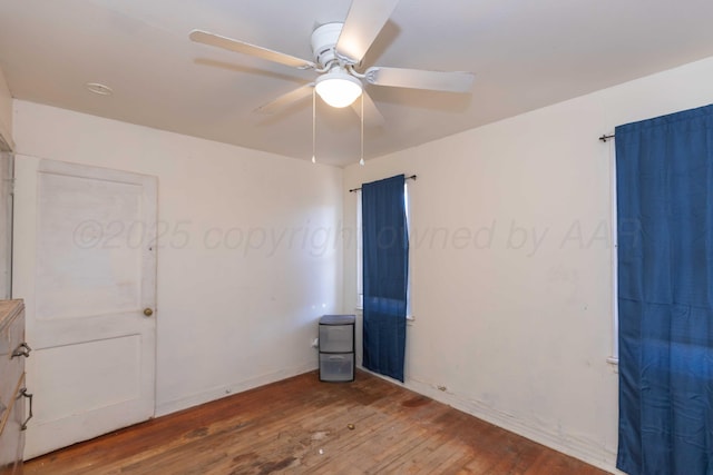 spare room with ceiling fan, wood-type flooring, and baseboards