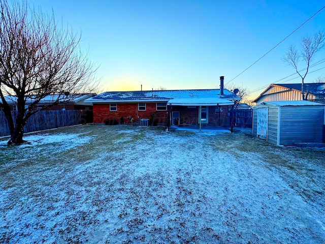 back house at dusk with a patio area, a shed, and a lawn