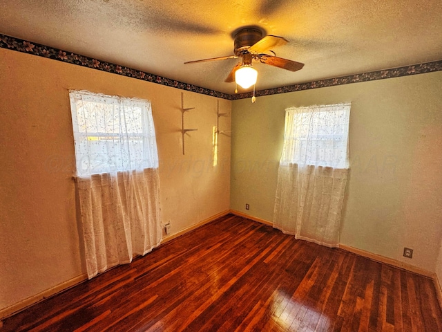 unfurnished room featuring ceiling fan, a wealth of natural light, dark hardwood / wood-style floors, and a textured ceiling