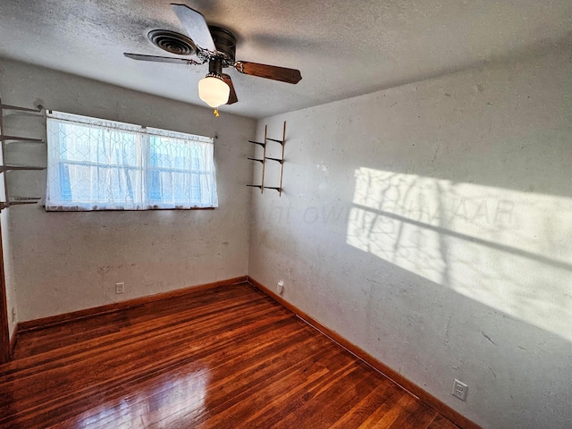 unfurnished room featuring ceiling fan, dark wood-type flooring, and a textured ceiling