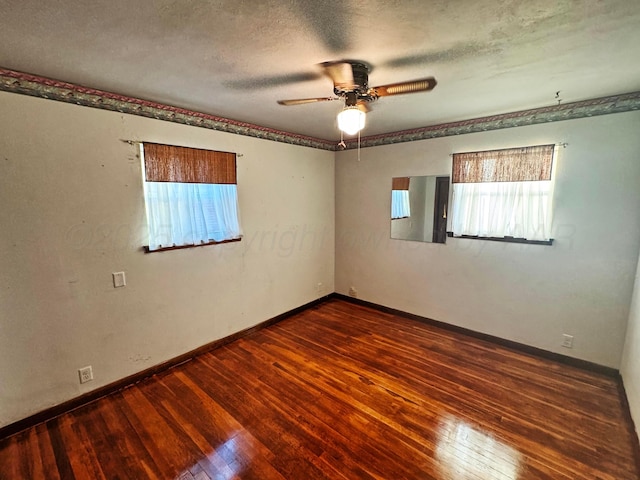 empty room featuring ceiling fan, dark wood-type flooring, and a textured ceiling