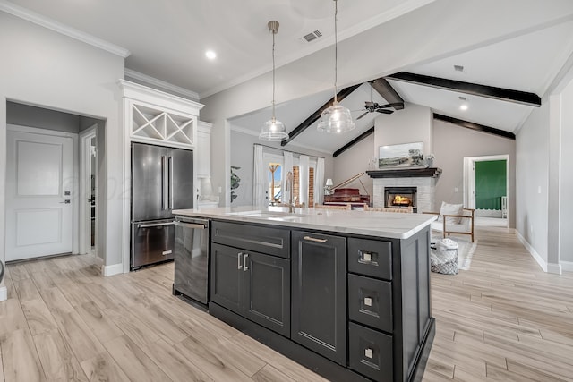 1600 NE 6th St, Dumas, TX 79029 - kitchen with visible vents, appliances with stainless steel finishes, a sink, a warm lit fireplace, and white cabinetry