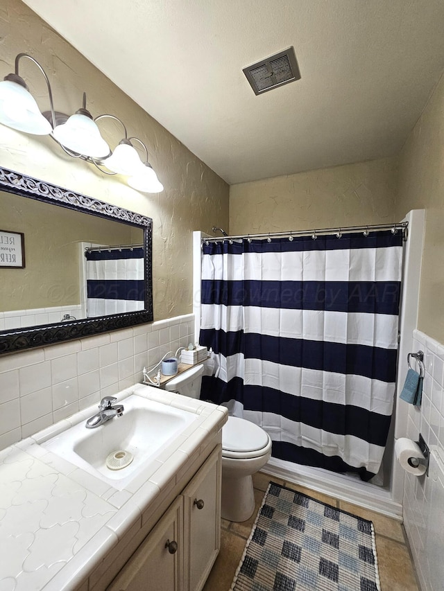 522 N Red Deer St, Pampa, TX 79065 - bathroom with tile walls, toilet, vanity, a textured wall, and tile patterned floors