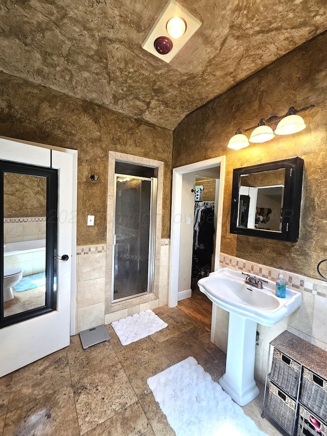 522 N Red Deer St, Pampa, TX 79065 - bathroom featuring tile walls, a shower stall, a spacious closet, toilet, and stone finish floors