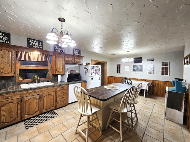 522 N Red Deer St, Pampa, TX 79065 - kitchen with a chandelier, white appliances, a sink, wainscoting, and wooden walls