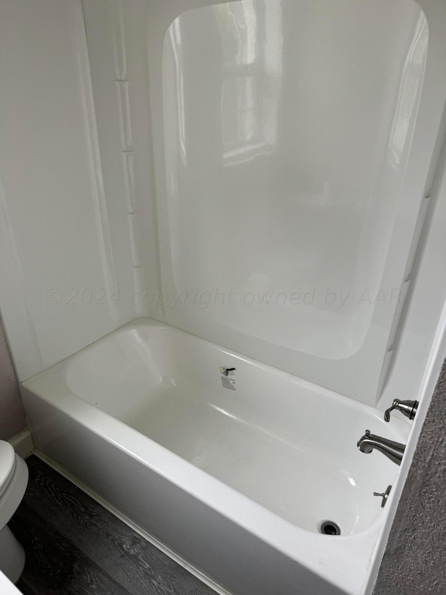 bathroom with a washtub, wood-type flooring, and toilet