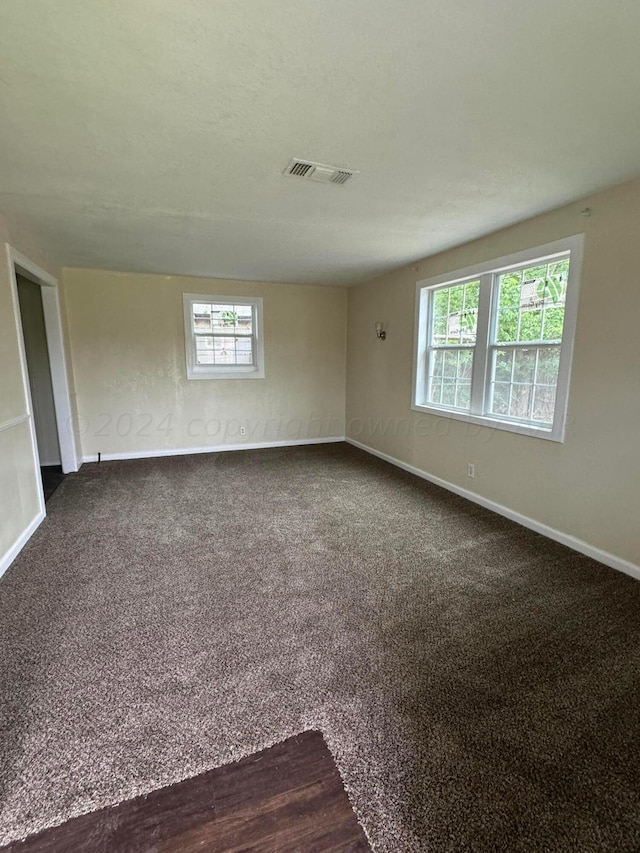 unfurnished room featuring dark carpet