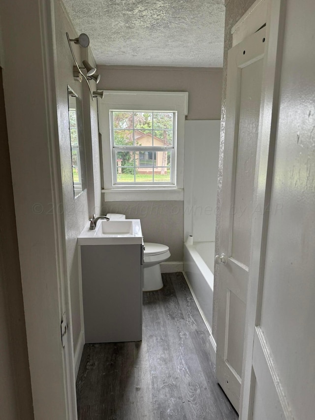 bathroom featuring toilet, vanity, wood-type flooring, and a textured ceiling