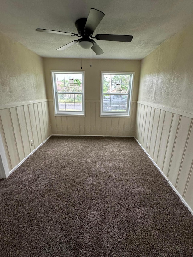 carpeted spare room featuring a textured ceiling and ceiling fan