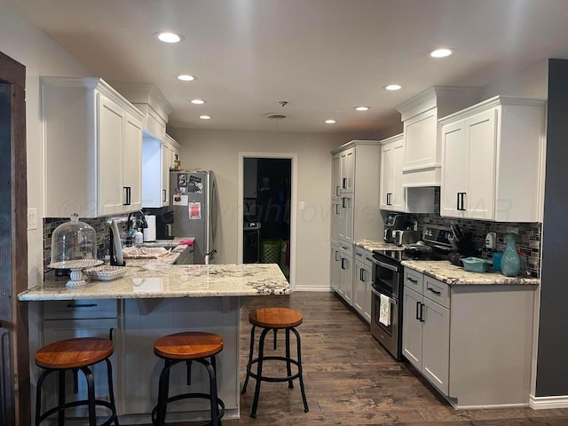 1711 N Holly Ln, Pampa, TX 79065 - kitchen featuring stainless steel appliances, recessed lighting, tasteful backsplash, a breakfast bar, and light stone counters