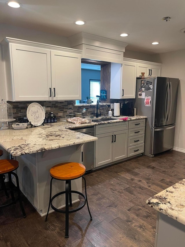 1711 N Holly Ln, Pampa, TX 79065 - kitchen featuring stainless steel appliances, a sink, dark wood finished floors, white cabinets, and backsplash