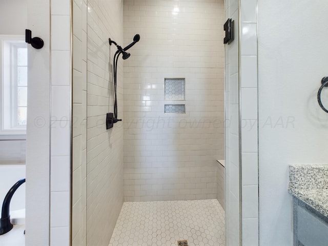 bathroom with a tile shower and vanity