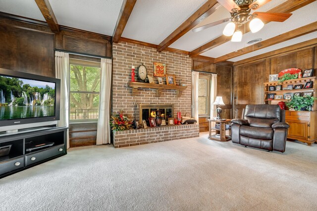 300 W 11th St, Wheeler, TX 79096 - carpeted living room with wooden walls, beamed ceiling, a ceiling fan, and a fireplace