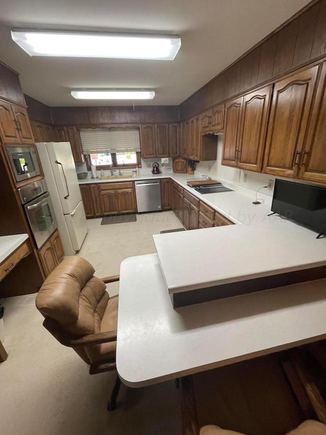 kitchen featuring a kitchen breakfast bar, kitchen peninsula, light colored carpet, and stainless steel appliances