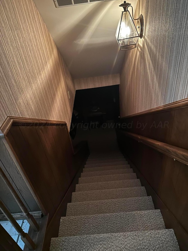 staircase with an inviting chandelier and lofted ceiling