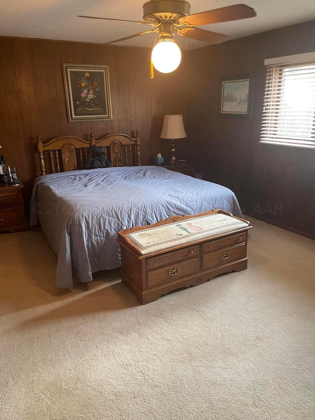 bedroom with ceiling fan, wooden walls, and carpet