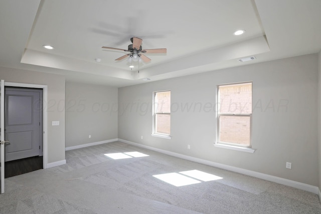 carpeted empty room featuring ceiling fan, visible vents, a raised ceiling, baseboards, and recessed lighting