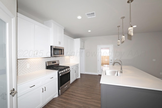 kitchen featuring backsplash, visible vents, a sink, dark wood-style floors, and stainless steel appliances