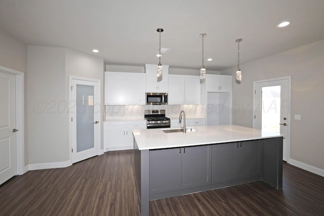 kitchen featuring a sink, dark wood finished floors, stainless steel appliances, white cabinetry, and decorative backsplash