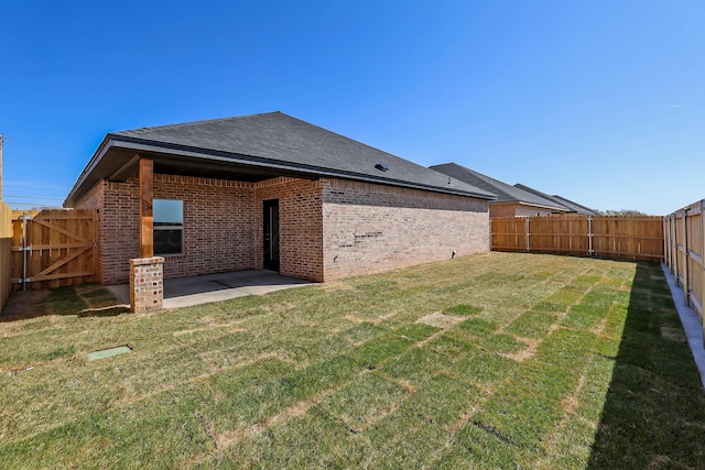rear view of property featuring roof with shingles, brick siding, a fenced backyard, a patio area, and a lawn