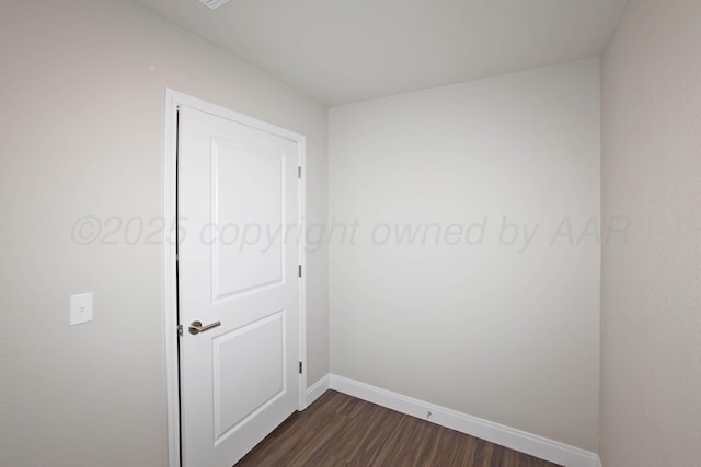 unfurnished room with baseboards and dark wood finished floors