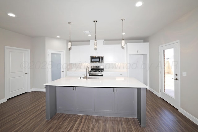 kitchen with stainless steel appliances, dark wood finished floors, decorative backsplash, and a sink
