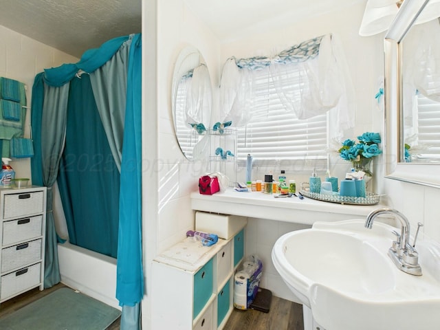 bathroom with tile walls, shower / tub combo, a textured ceiling, a sink, and wood finished floors