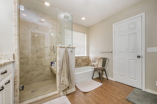 bathroom featuring shower with separate bathtub, hardwood / wood-style floors, and vanity