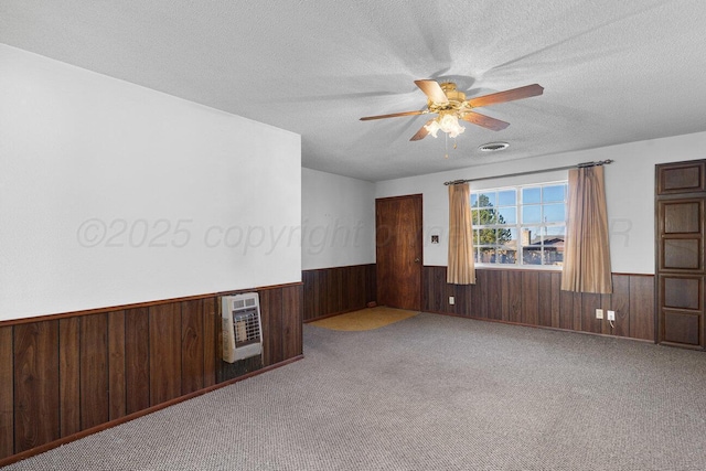 empty room featuring heating unit, a wainscoted wall, a textured ceiling, and wooden walls