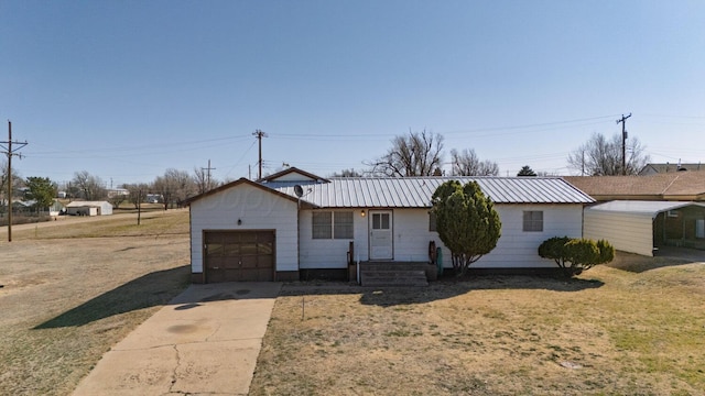 ranch-style home featuring concrete driveway, a garage, and metal roof