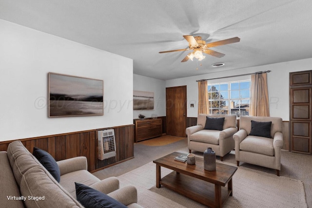 living room with heating unit, a wainscoted wall, ceiling fan, wood walls, and light carpet