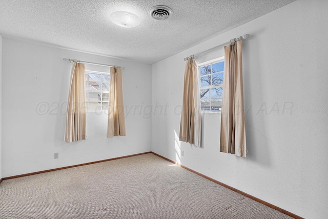 spare room with baseboards, visible vents, carpet floors, and a textured ceiling