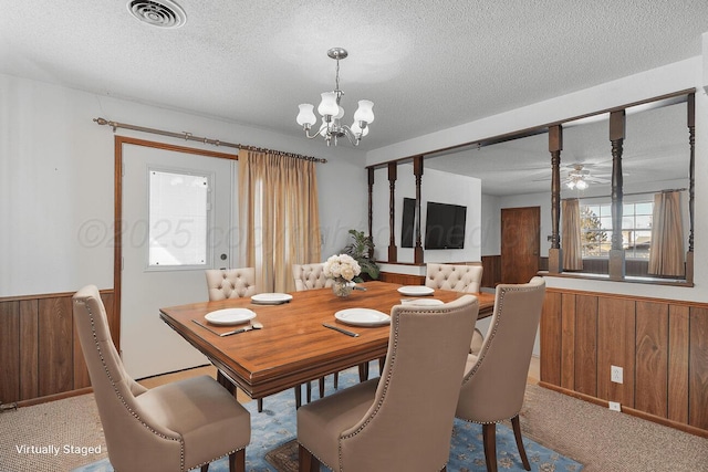 carpeted dining room with a wainscoted wall, visible vents, and wood walls