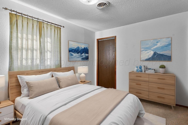 bedroom featuring visible vents, light carpet, a textured ceiling, and a closet